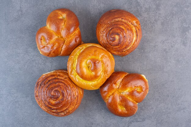 Five sweet buns arranged on marble.