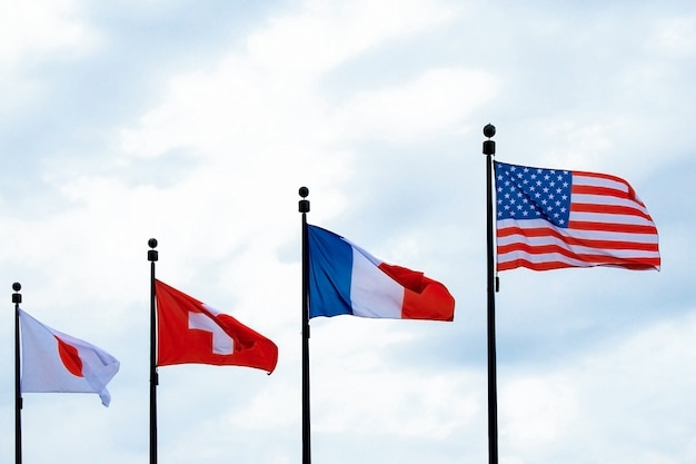 Flags of  the usa france switzerland japan waving in the sky