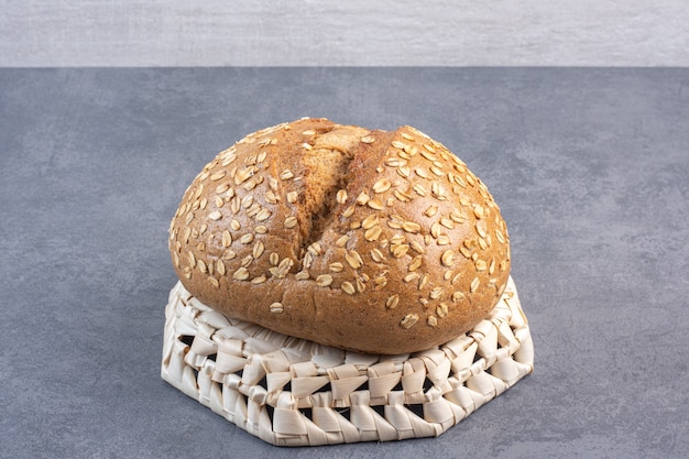 Free photo flake covered loaf of bread on an upside-down basket on marble.