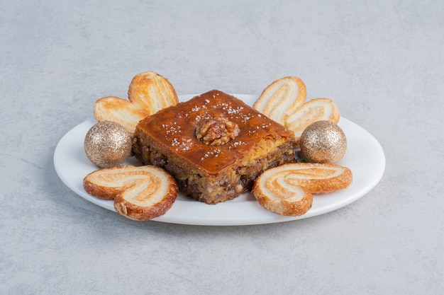 Foto gratuita biscotti a fiocchi e bakhlava su un piatto con una pallina sulla superficie di marmo