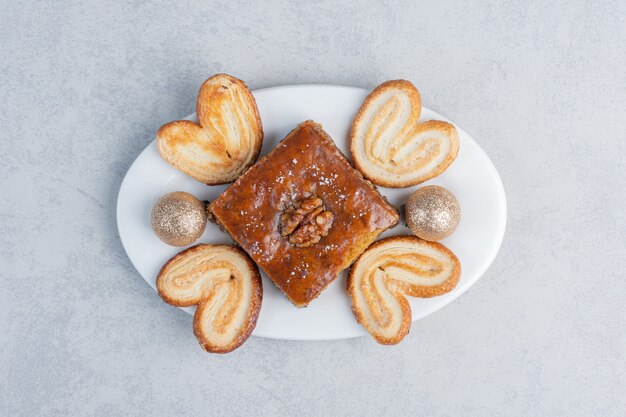 Free photo flaky cookies and a bakhlava on a platter with a bauble on marble surface