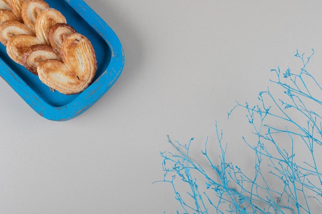 Flaky cookies bundled on a blue platter on marble background.