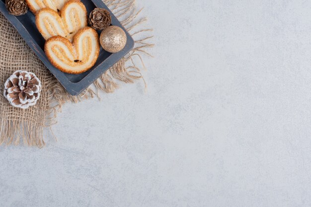 Flaky cookies and christmas adornments on a small tray on marble surface