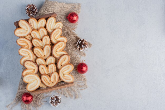 Слоеное печенье, сложенное в деревянную корзину и окруженное рождественскими украшениями на мраморной поверхности