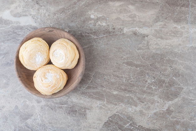 Flaky cookies in a small bowl on marble surface