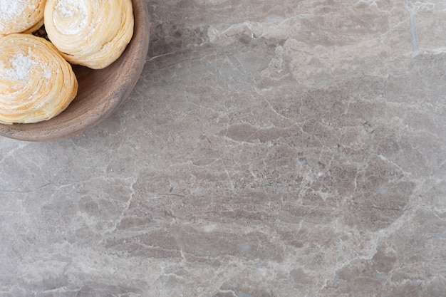 Flaky cookies in a small bowl on marble surface