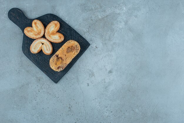 フレーク状のクッキーと大理石の背景のボード上の小さなケーキ。高品質の写真