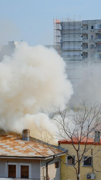 近所の燃えている家から炎が出ています。都市景観の火の屋根から出る煙。破壊された建物から出る爆発による危険な煙とスモッグ