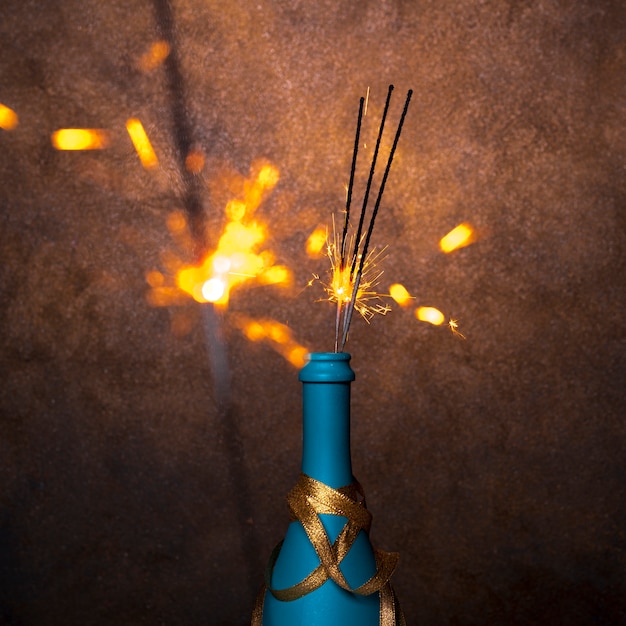 Free photo flaming bengal lights in blue bottle of drink