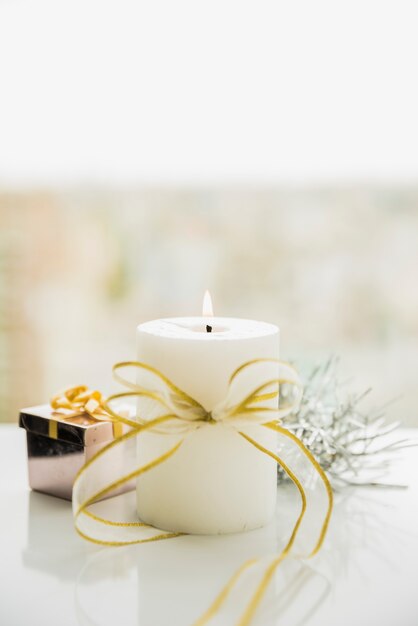 Flaming candle with bow near window