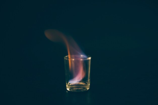 Flaming tequila shot glass on black backdrop