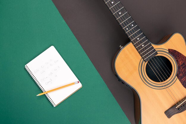 Flat lay acoustic guitar and notebook on color background