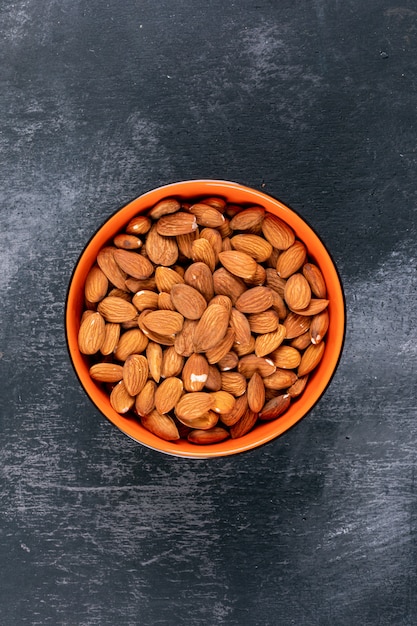 Flat lay almond in bowl on black stone table.