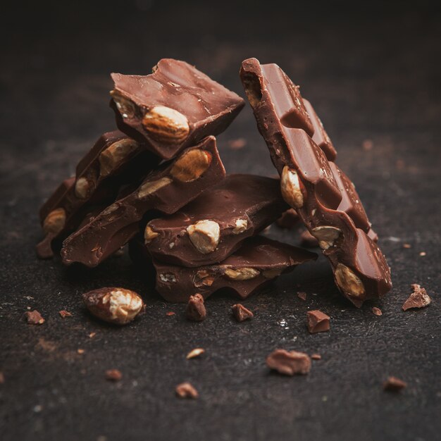 Flat lay almonds with chocolate on dark brown textured.