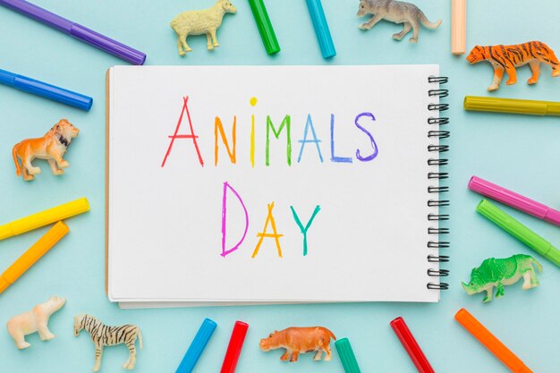 Flat lay of animal figurines and colorful writing on notebook for animal day