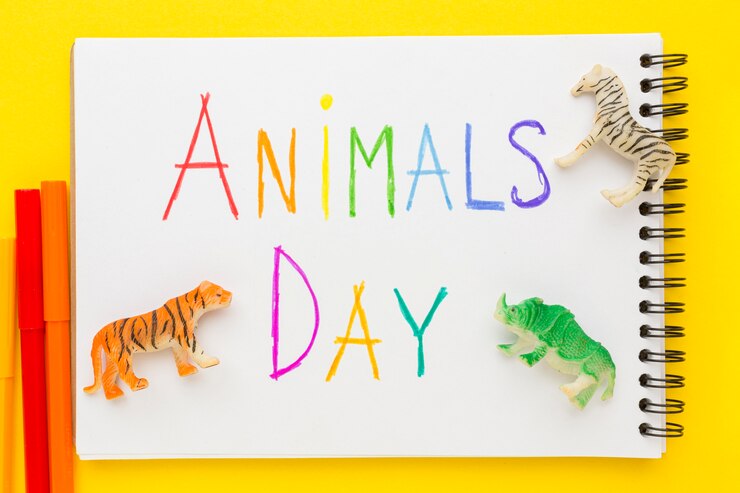 Free Photo flat lay of animal figurines with colorful writing on notebook for animal day