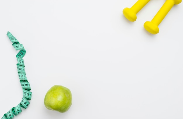 Flat lay of apple with measuring tape and weights