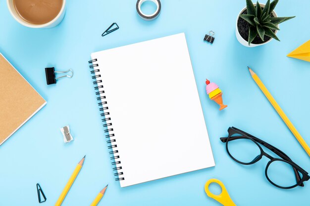 Flat lay arrangement of desk elements on blue background