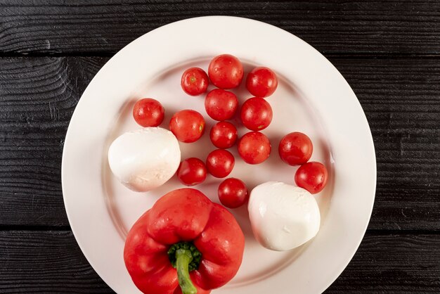 Flat lay of arrangement of tomatoes and pizza on wooden table