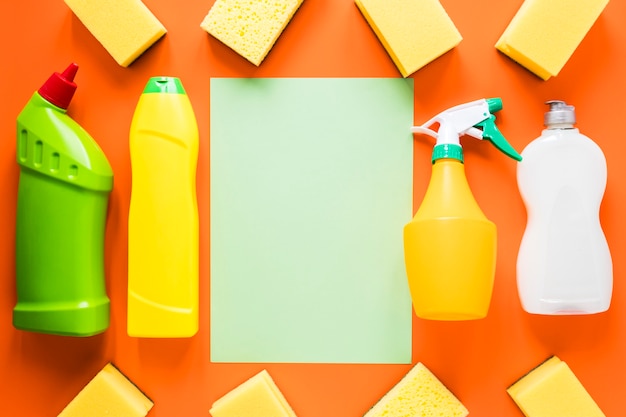 Flat lay arrangement with cleaning products on orange background