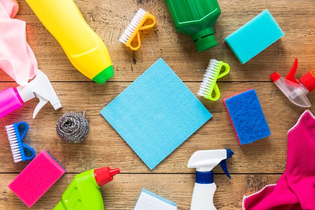Flat lay arrangement with cleaning products and wooden background