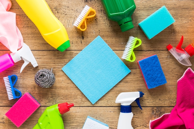 Flat lay arrangement with cleaning products and wooden background