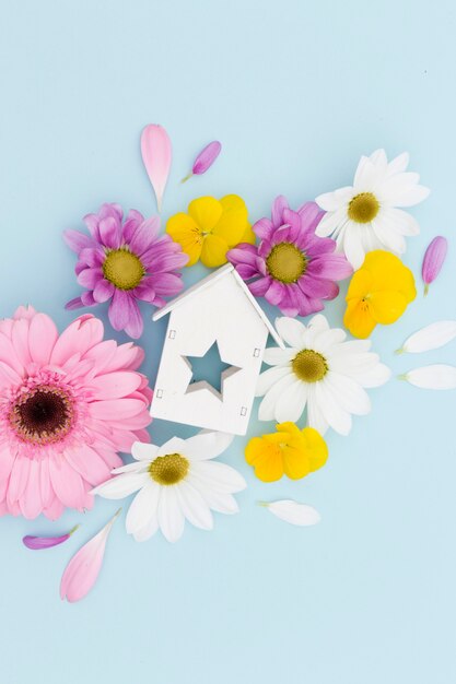 Flat lay arrangement with flowers and wooden house