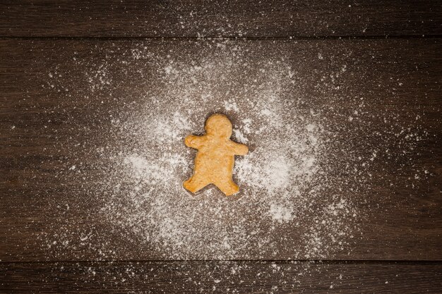 Flat lay arrangement with gingerbread man cookie and flour