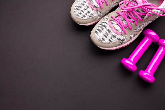 Flat lay arrangement with pink shoes and dumbbells