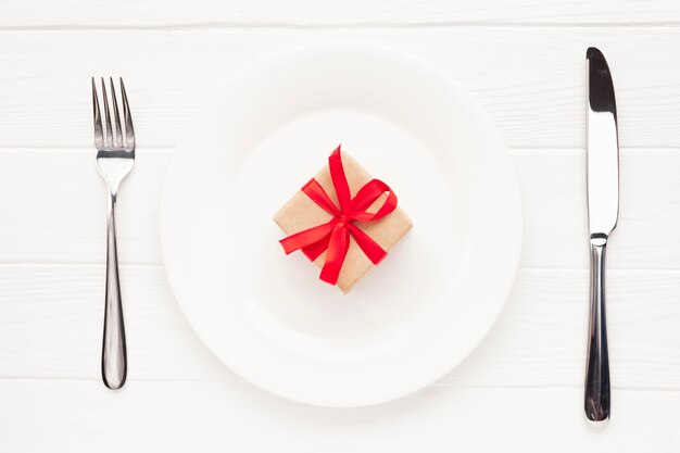 Flat lay arrangement with plate, cutlery and gift