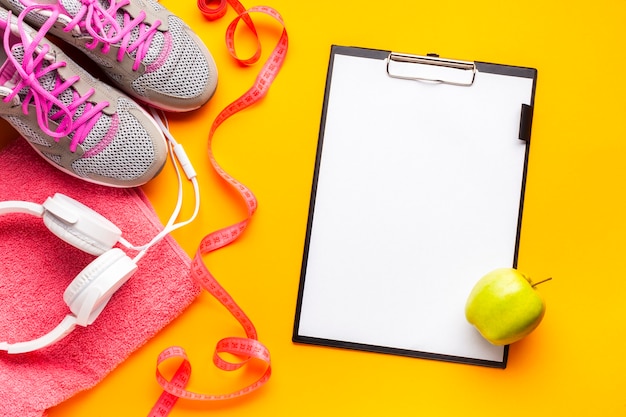 Free photo flat lay arrangement with sports items, clipboard and apple