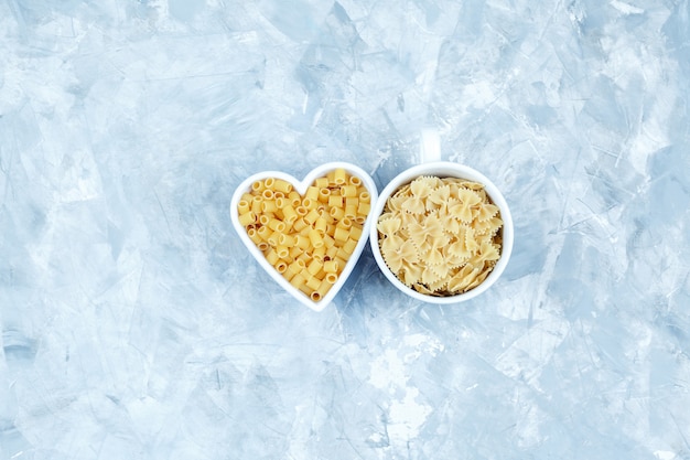 Flat lay assorted pasta in bowls on grungy grey background. horizontal