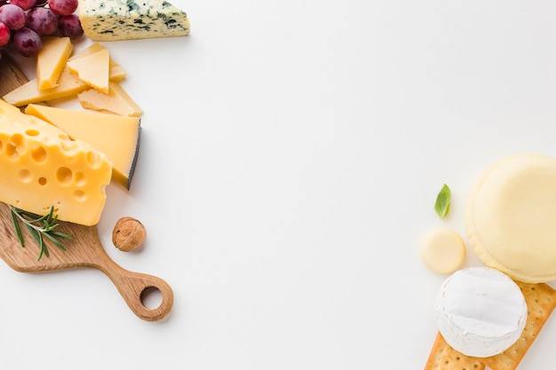 Flat lay assortment of cheese on wooden cutting board