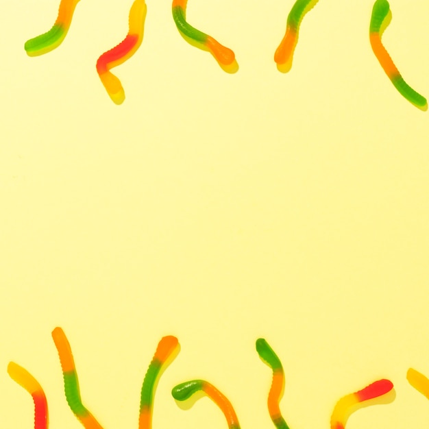 Плоский набор разноцветных конфет на желтом фоне с копией пространства