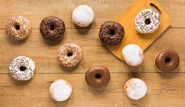 Flat lay of assortment of doughnut on wooden surface