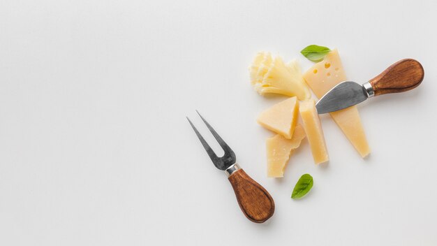 Flat lay assortment of gourmet cheese and cheese knives with copy space