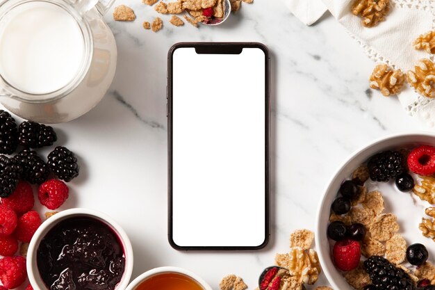 Flat lay assortment of healthy bowl cereals with empty screen smartphone