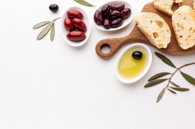 Flat lay assortment of olives bread slices and olive oil with copy space