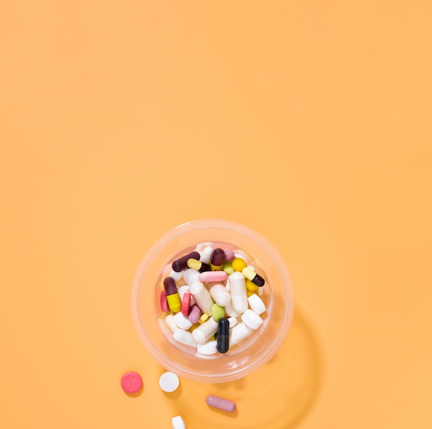 Flat lay of assortment of pills in plastic cup with copy space