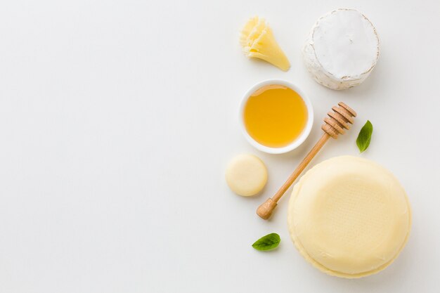 Flat lay assortment of round cheese and honey with copy space