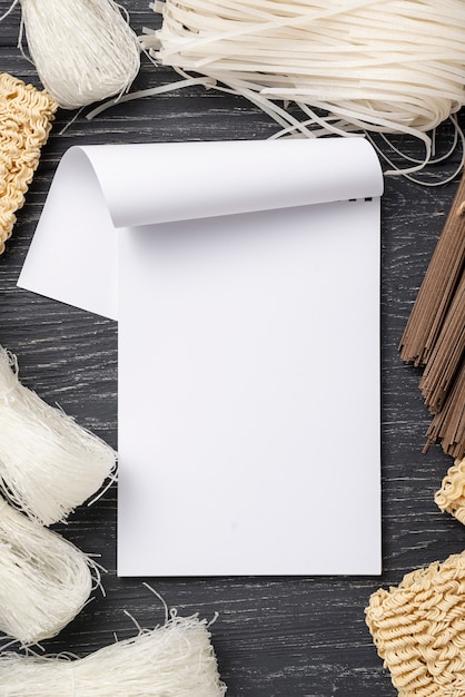 Flat lay assortment of uncooked noodles with blank notebook