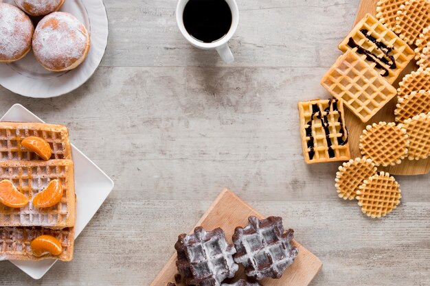 Flat lay of assortment of waffles with coffee and doughnuts
