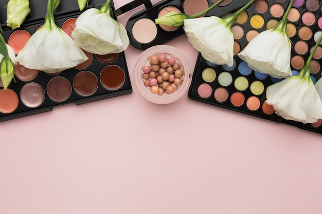 Flat lay assortment with make-up palettes and flowers