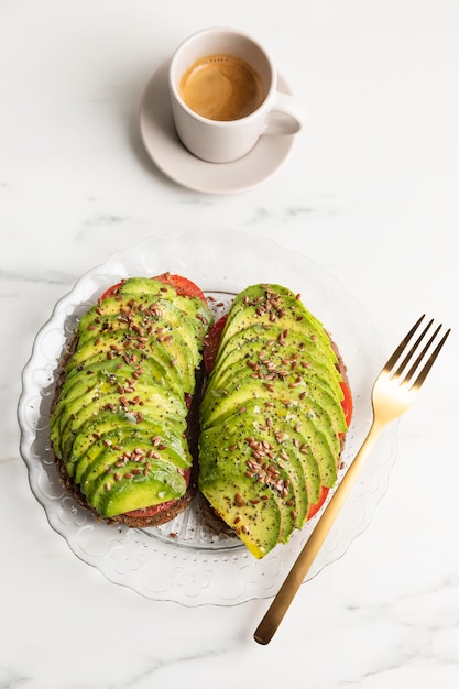 Flat lay of avocado toast on plate with cutlery and coffee