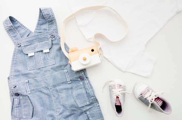 Flat lay baby clothes with photo camera