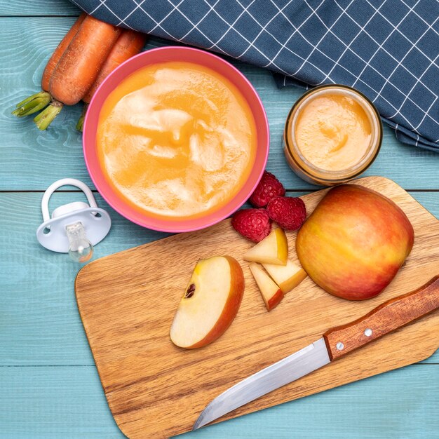 Плоская кладка детского питания в миске с фруктами и морковью