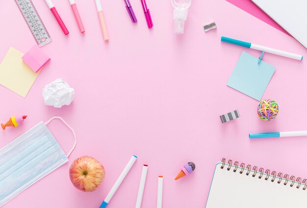 Flat lay of back to school supplies with apple and face mask