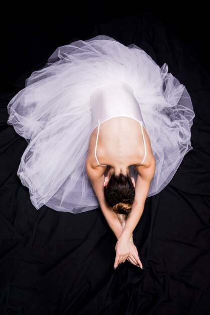 Плоская балерина лежит на черном фоне