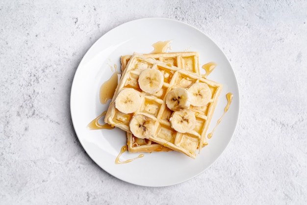 Flat lay of banana slices and honey on waffles