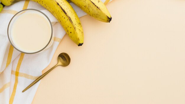 Flat lay of banana smoothie with golden spoon